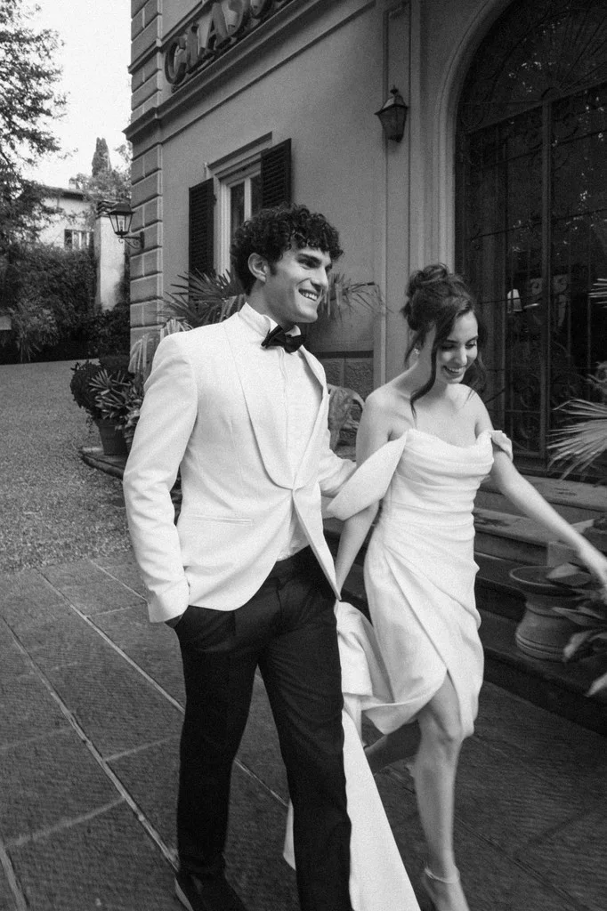 Laughing couple walking hand in hand past a villa entrance