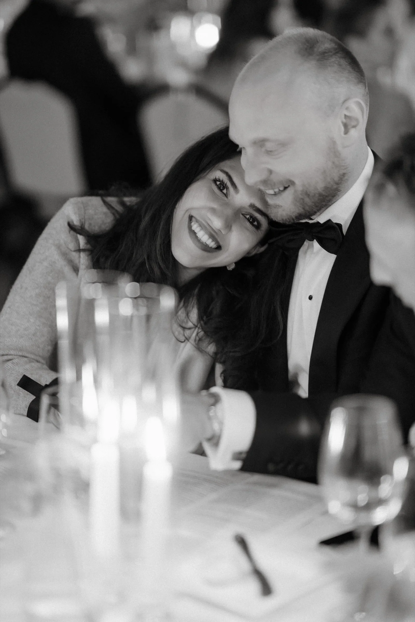 Guest resting her head on the shoulder of a man in a bow tie at the table