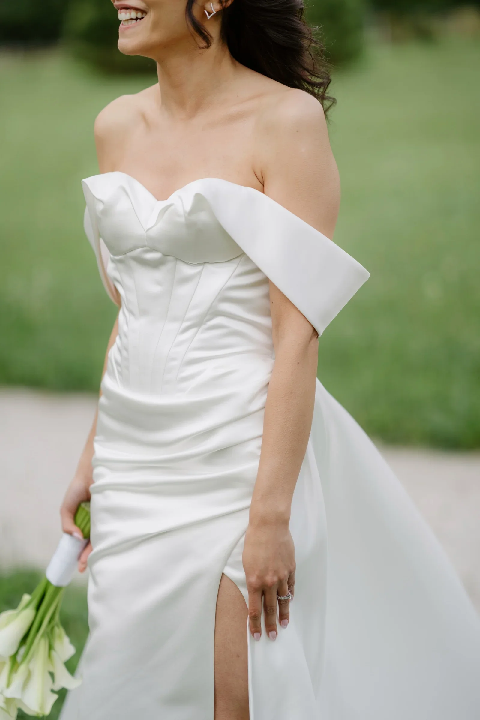 Bride in a strapless off-shoulder gown walking with a calla bouquet