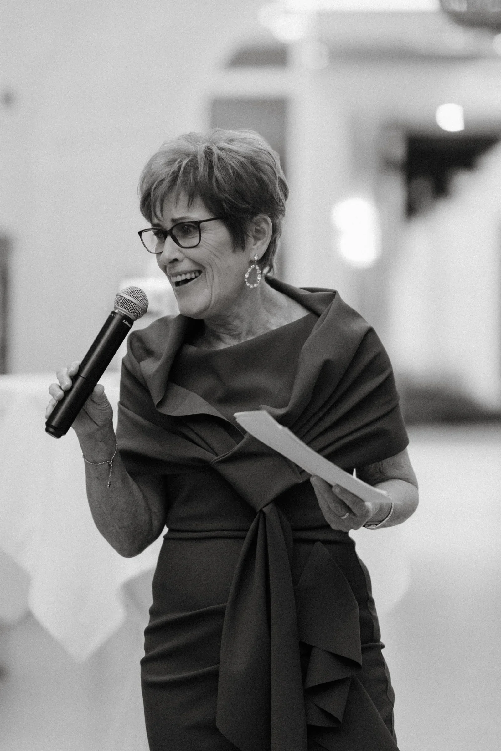 Woman in a dark dress giving a speech into a microphone, black and white