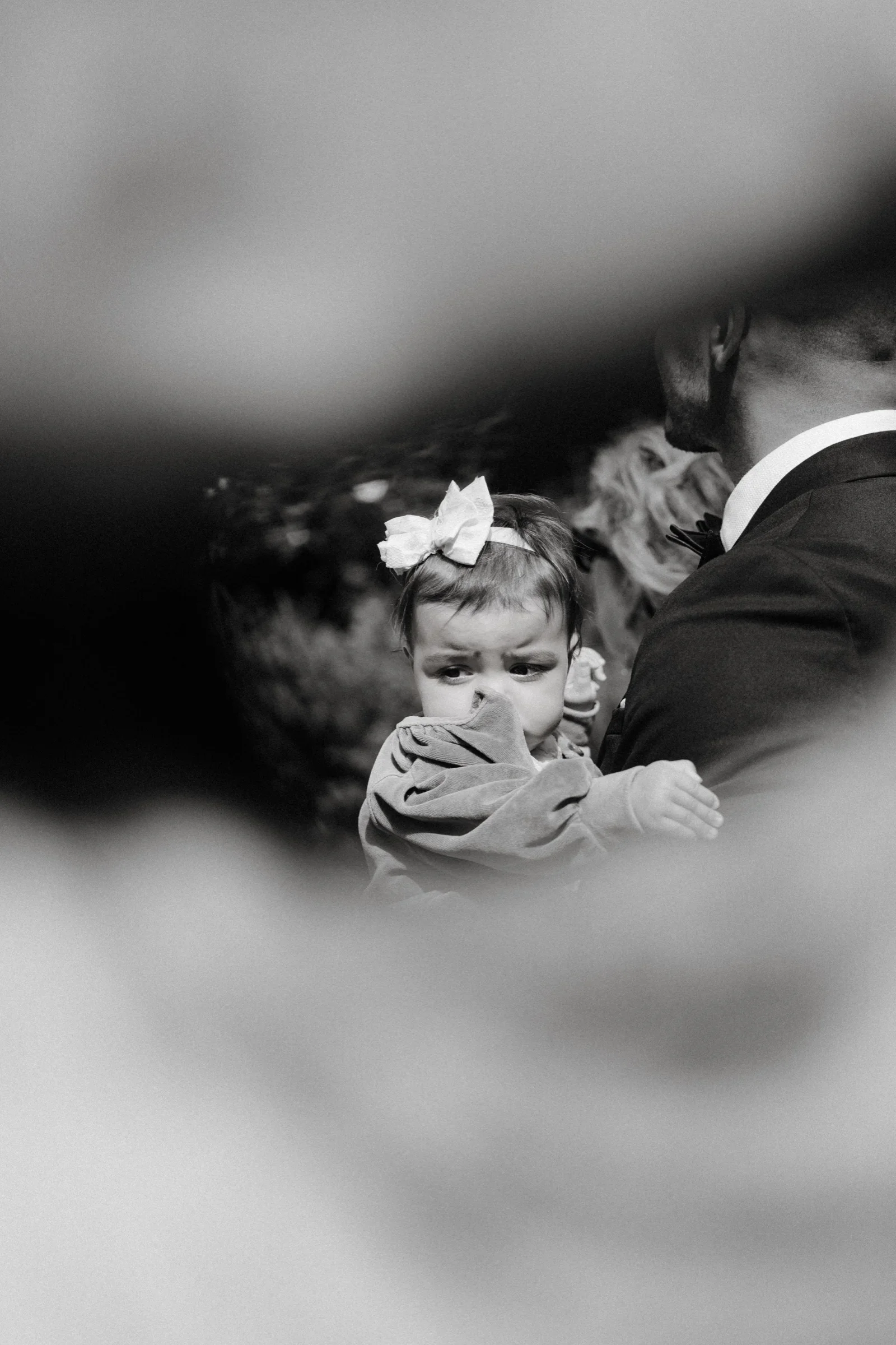 Black and white close-up of a little girl with a flower clip seen through a blurred frame