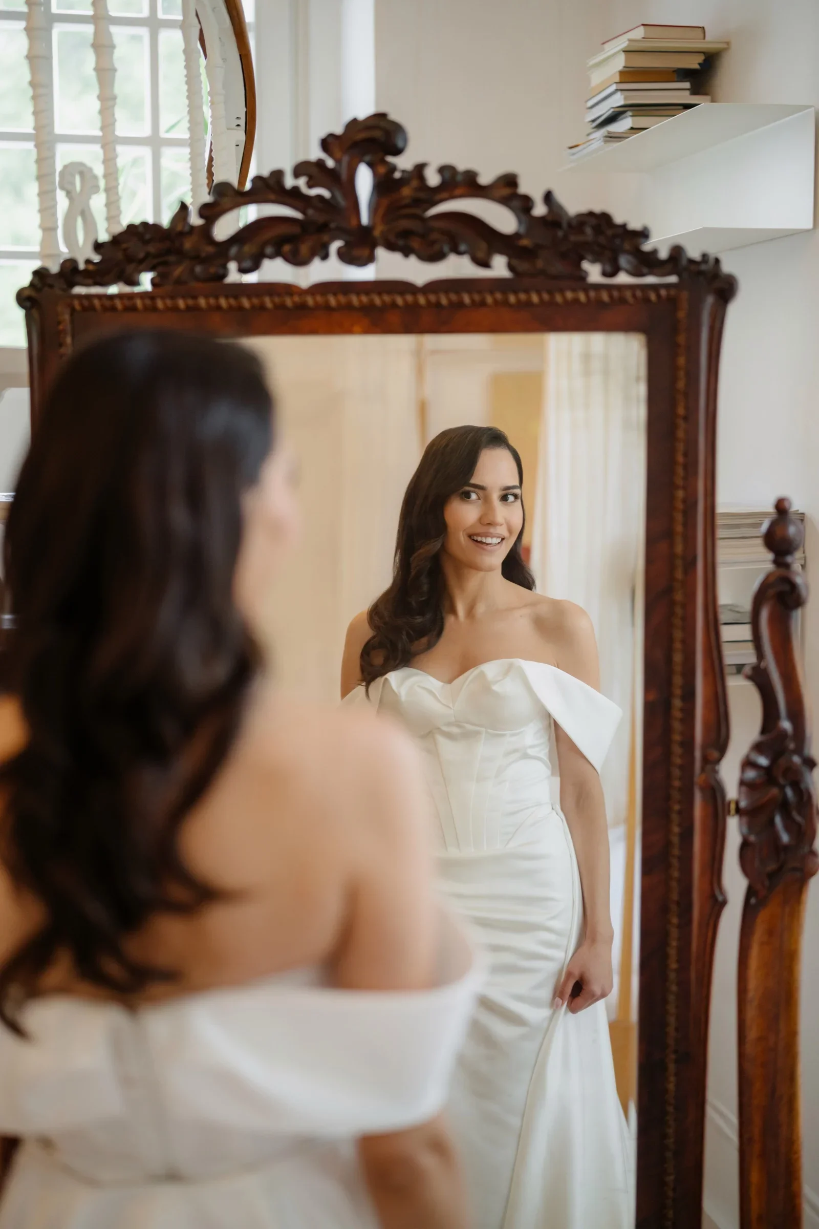 Bride in an off-shoulder wedding dress reflected in an antique mirror
