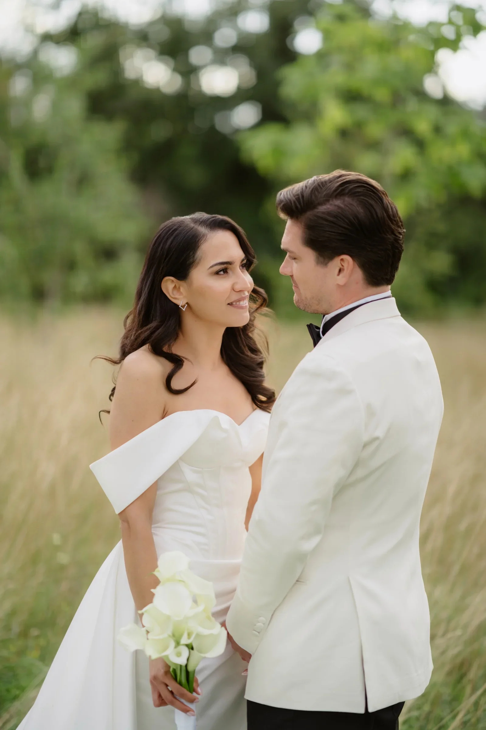 Couple in a field of tall grass with a white calla bouquet