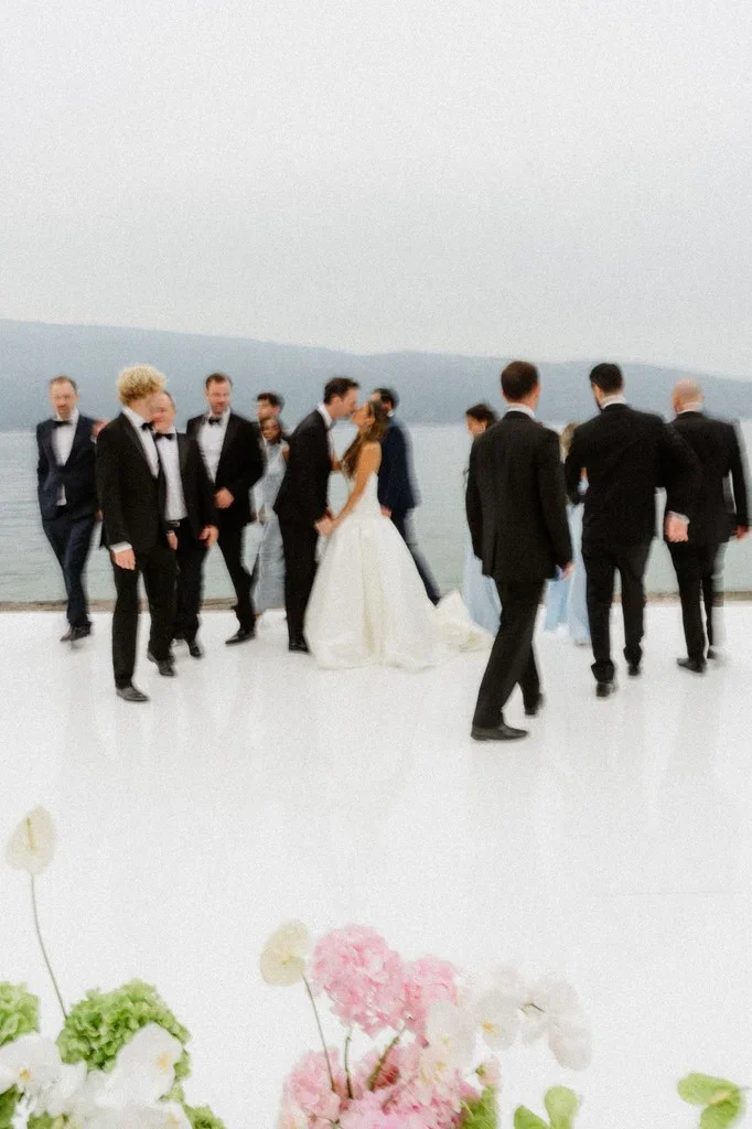 Wedding party gathered on a white terrace above a misty lake