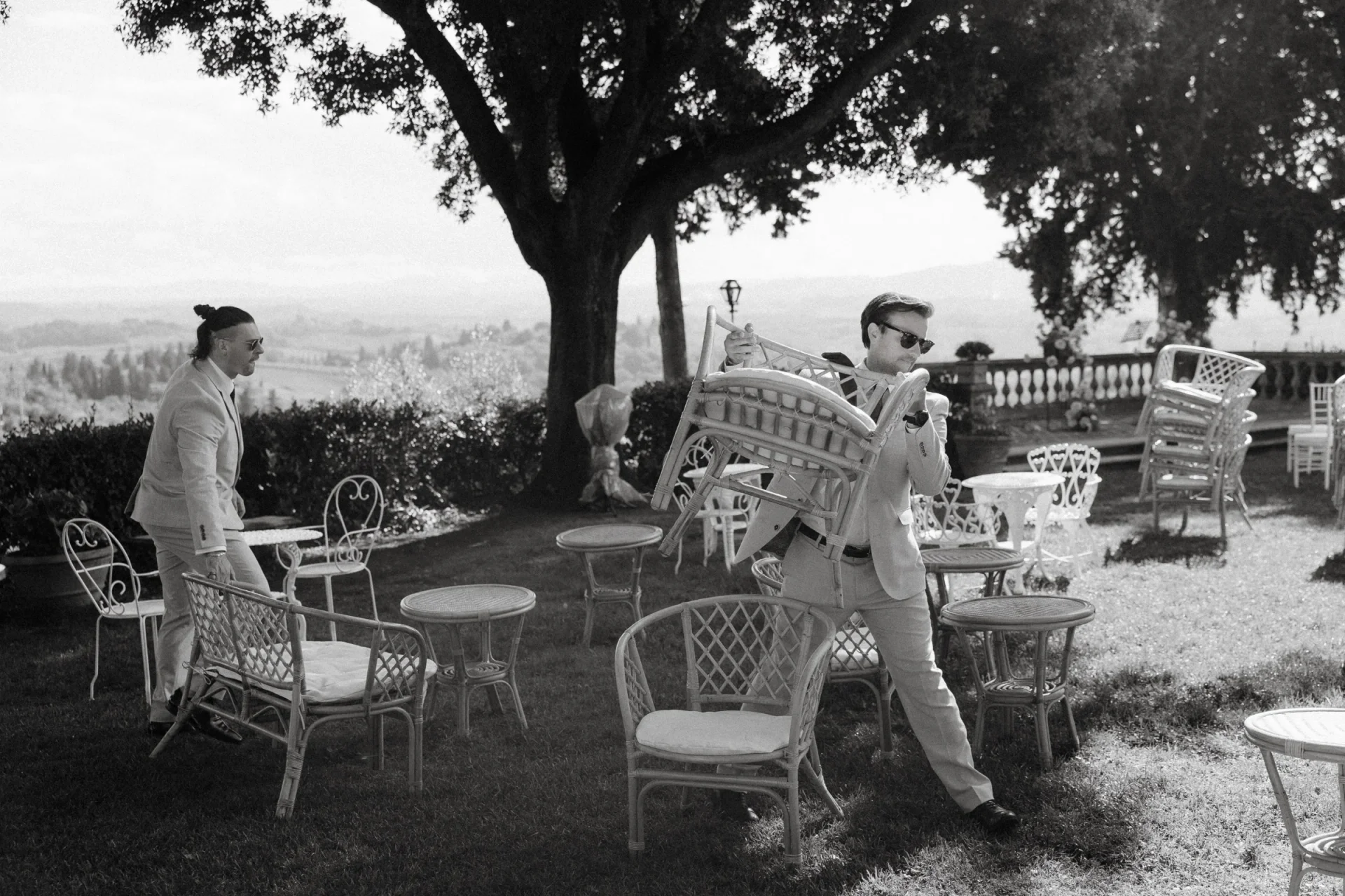 Black and white: the bride and groom apart at the garden table before they see each other