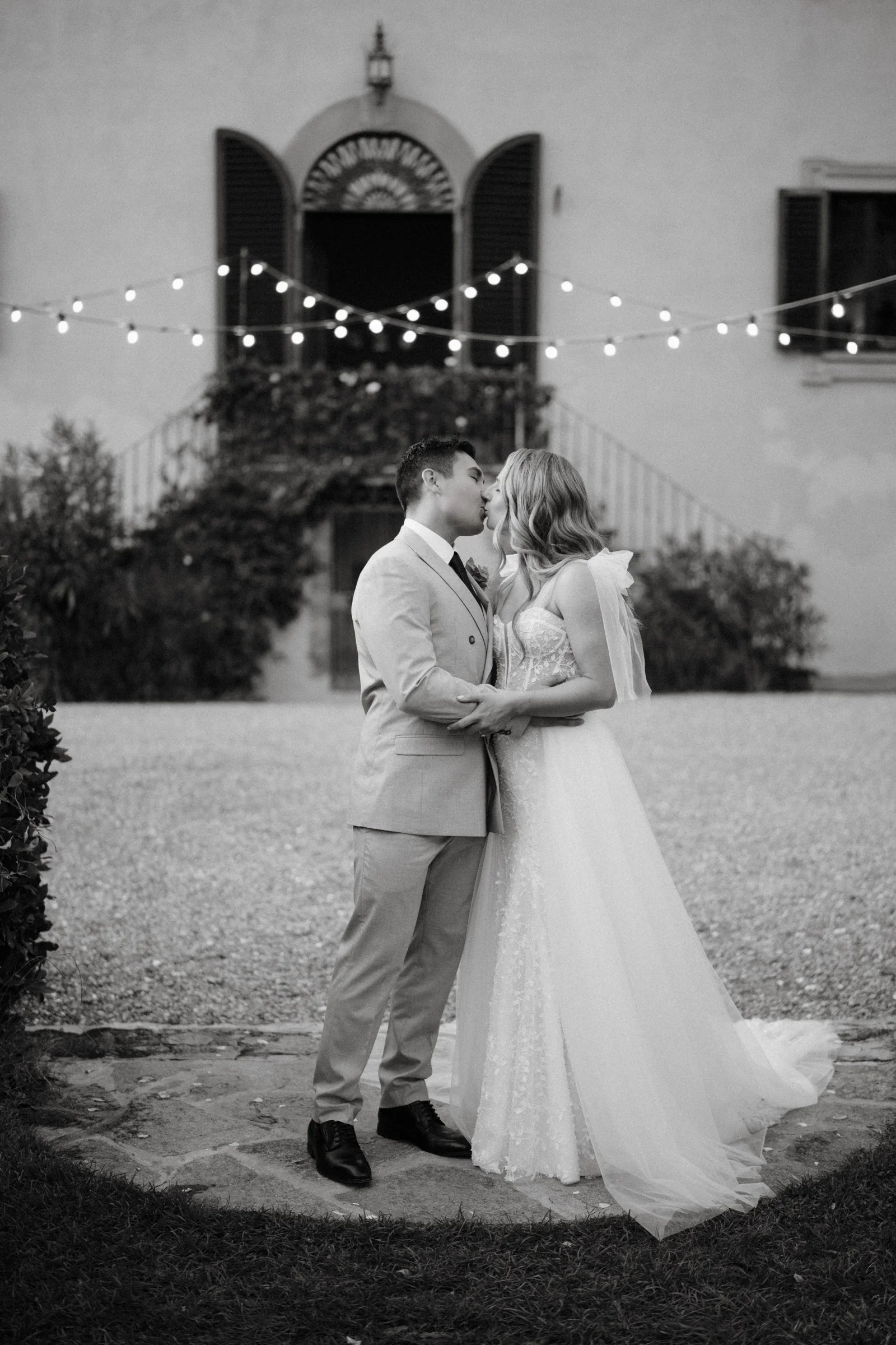Black and white: the couple close together on the drive beneath the festoon lights