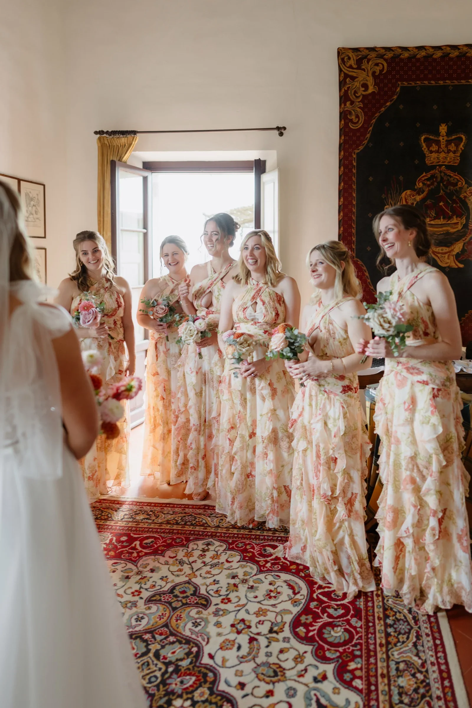 The bride standing with her bridesmaids in patterned gowns in the villa's sunlit salon