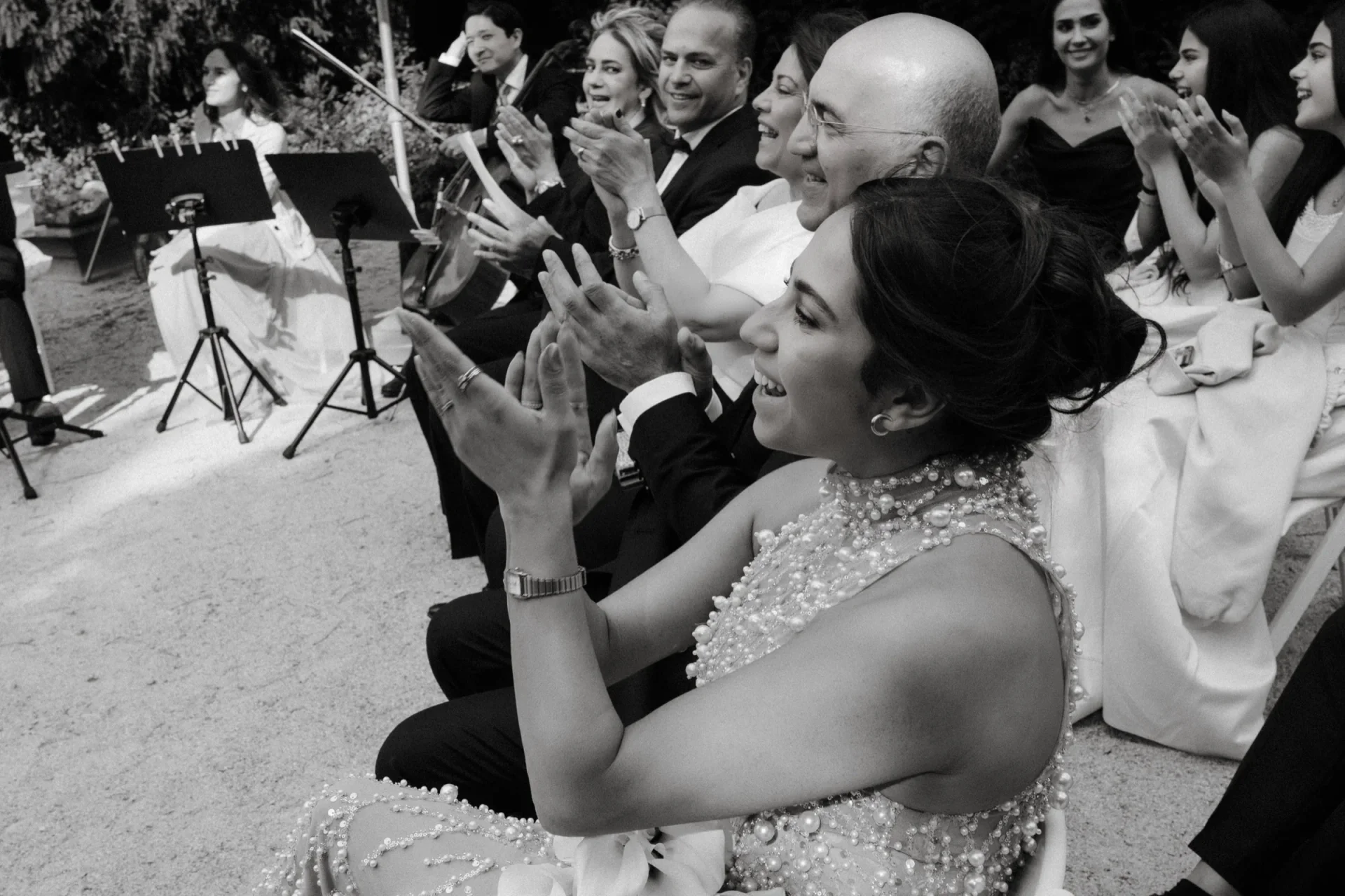 Black and white photo of a smiling guest in a sparkling dress applauding