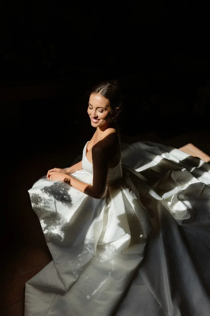 Bride seated in dappled sunlight with her skirt spread around her