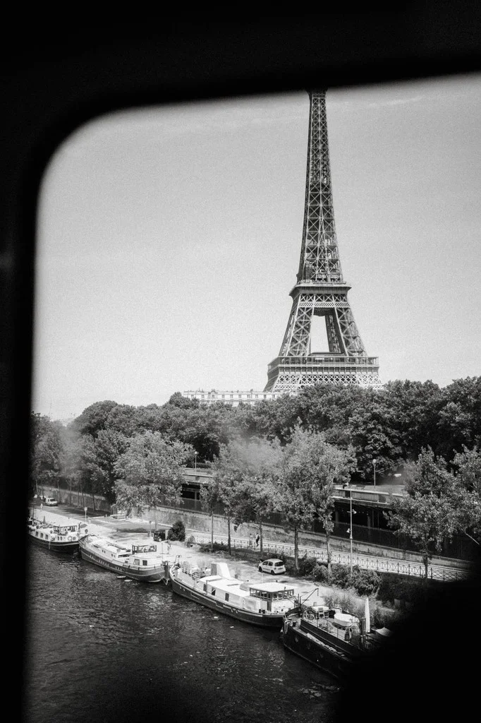 Eiffel Tower framed by a window above barges on the Seine