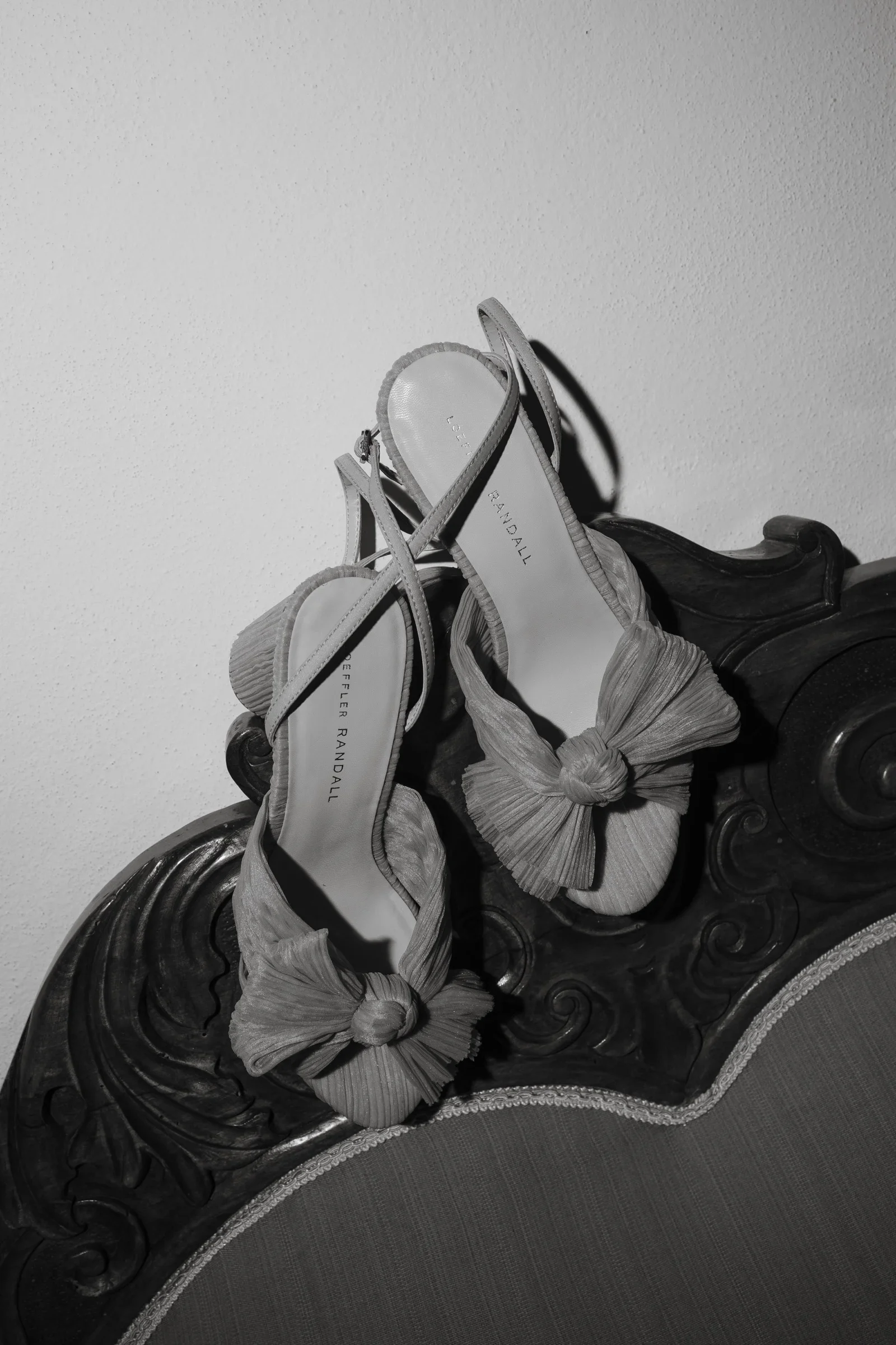 Black and white still life of the bow-front bridal shoes on a carved chest
