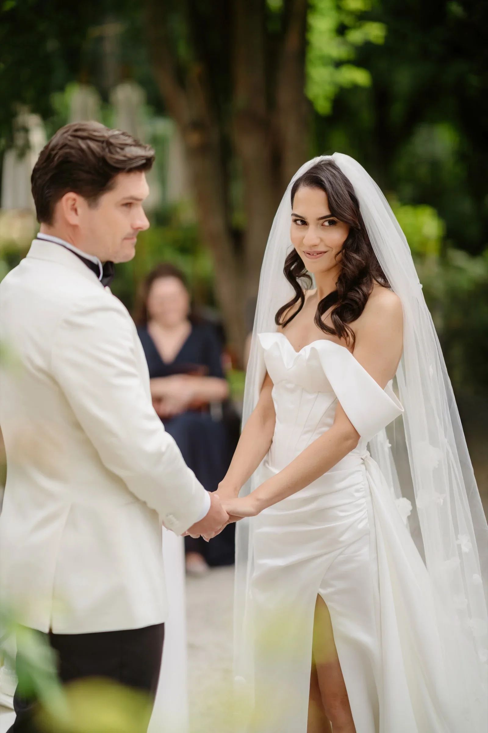 Bride and groom holding hands during the ceremony, he in a white dinner jacket