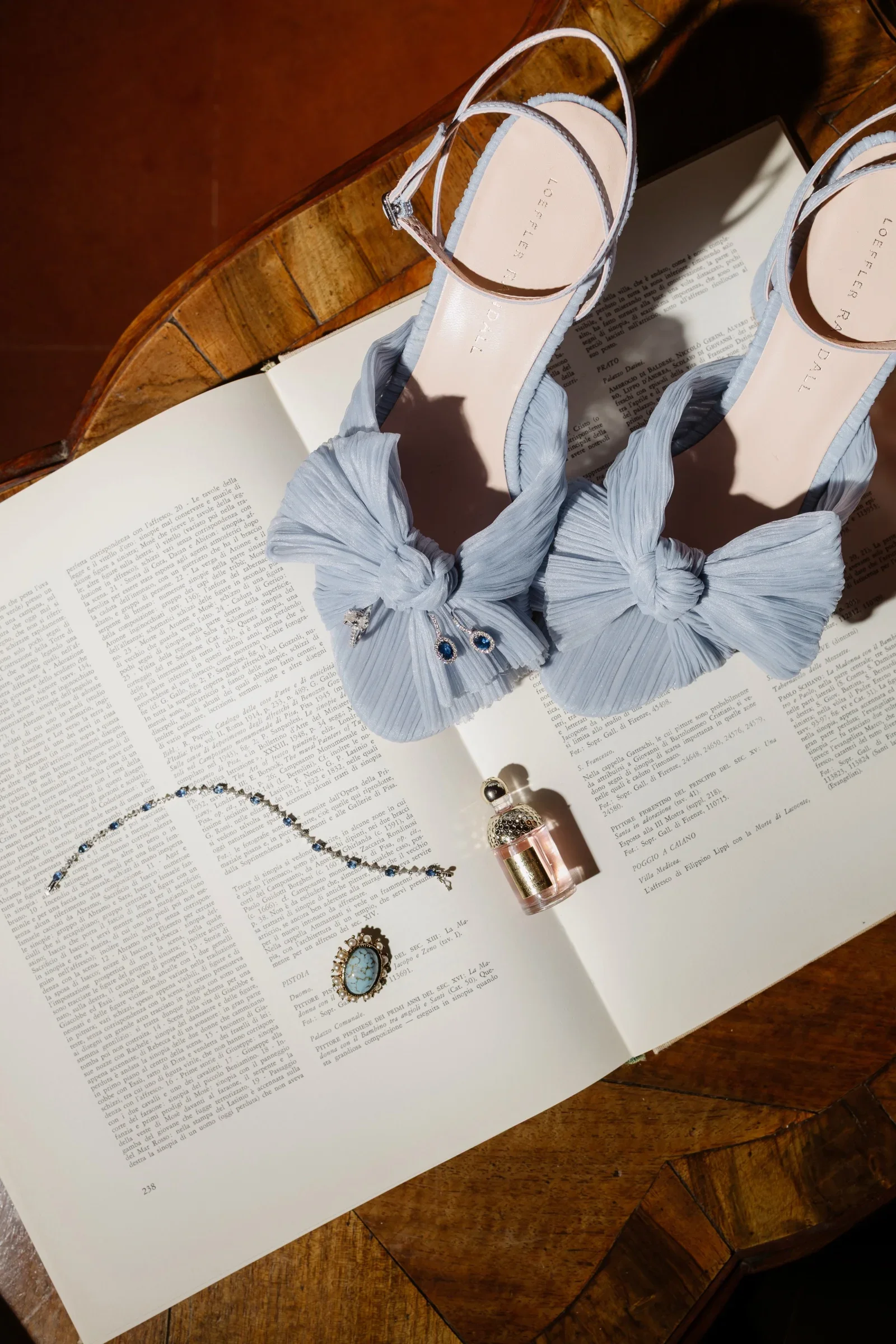 The bride's pale blue bow-tied sandals and a necklace resting on an open book