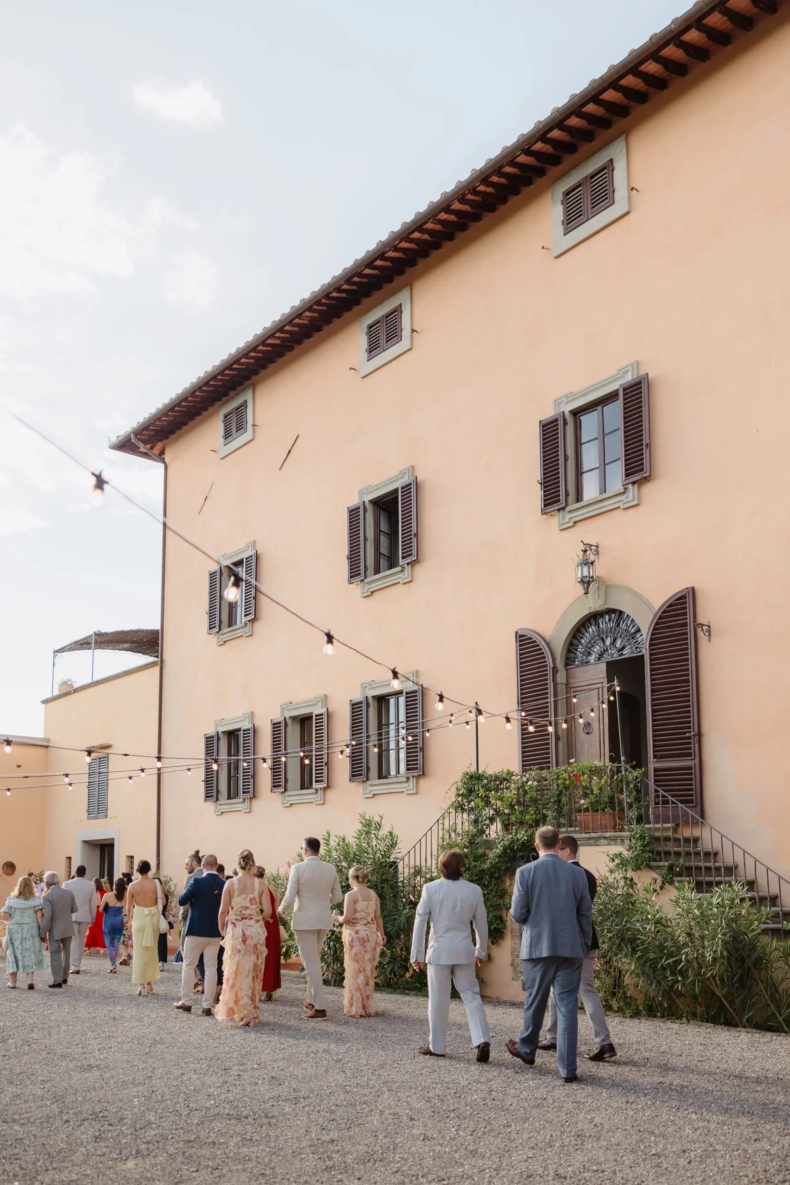 Guests crossing the gravel towards the villa after the ceremony, lights overhead