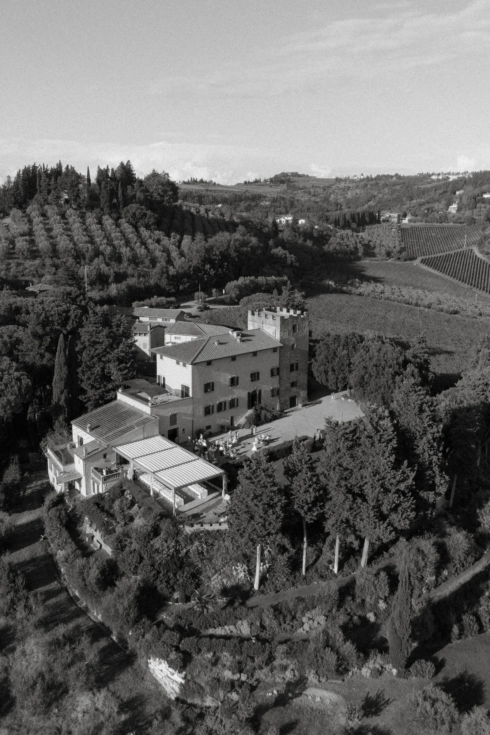 Black and white aerial of the villa among cypresses and olive terraces