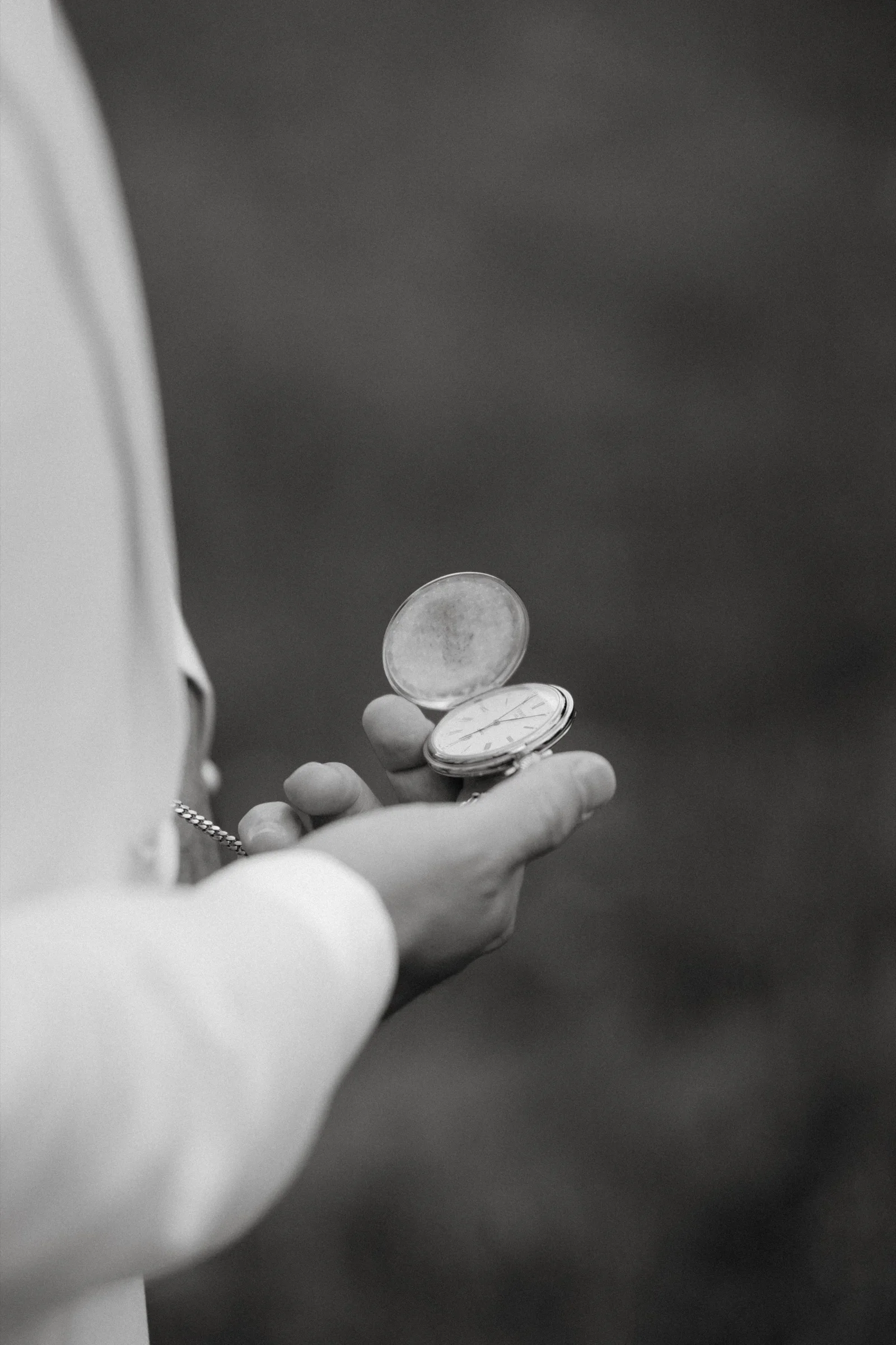 Hand holding two wedding rings against a dark blurred background, black and white