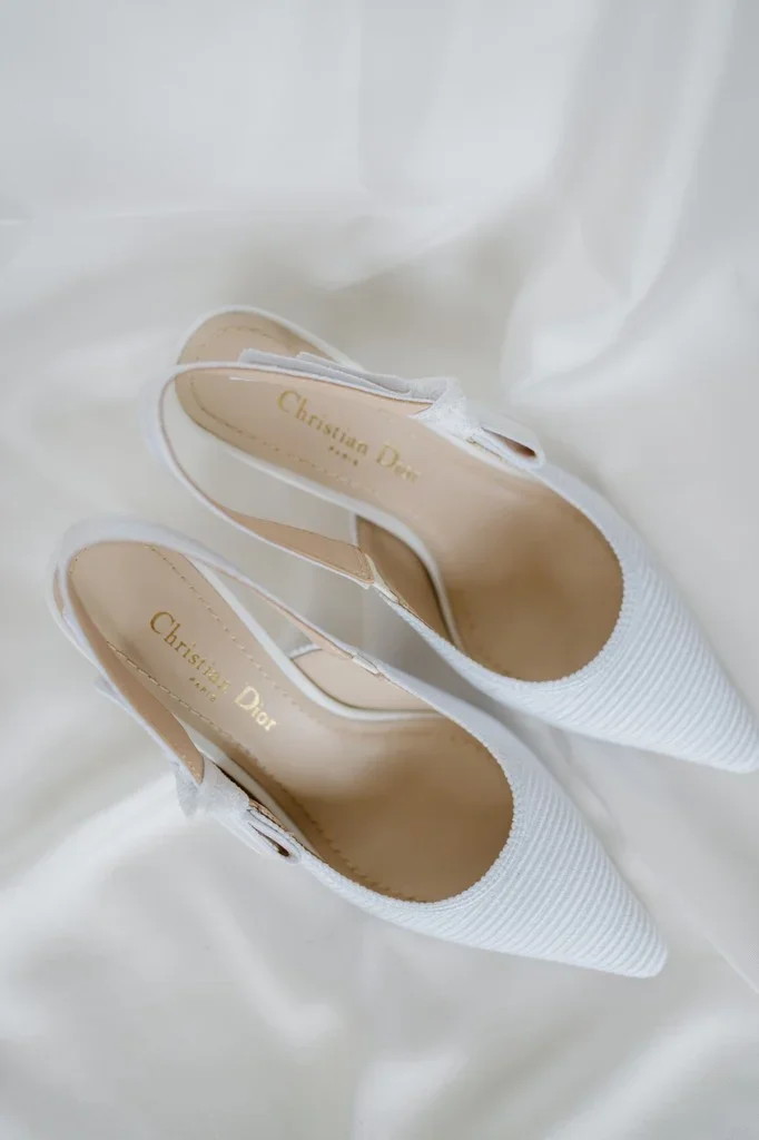 White bridal slingback heels resting on soft silk fabric
