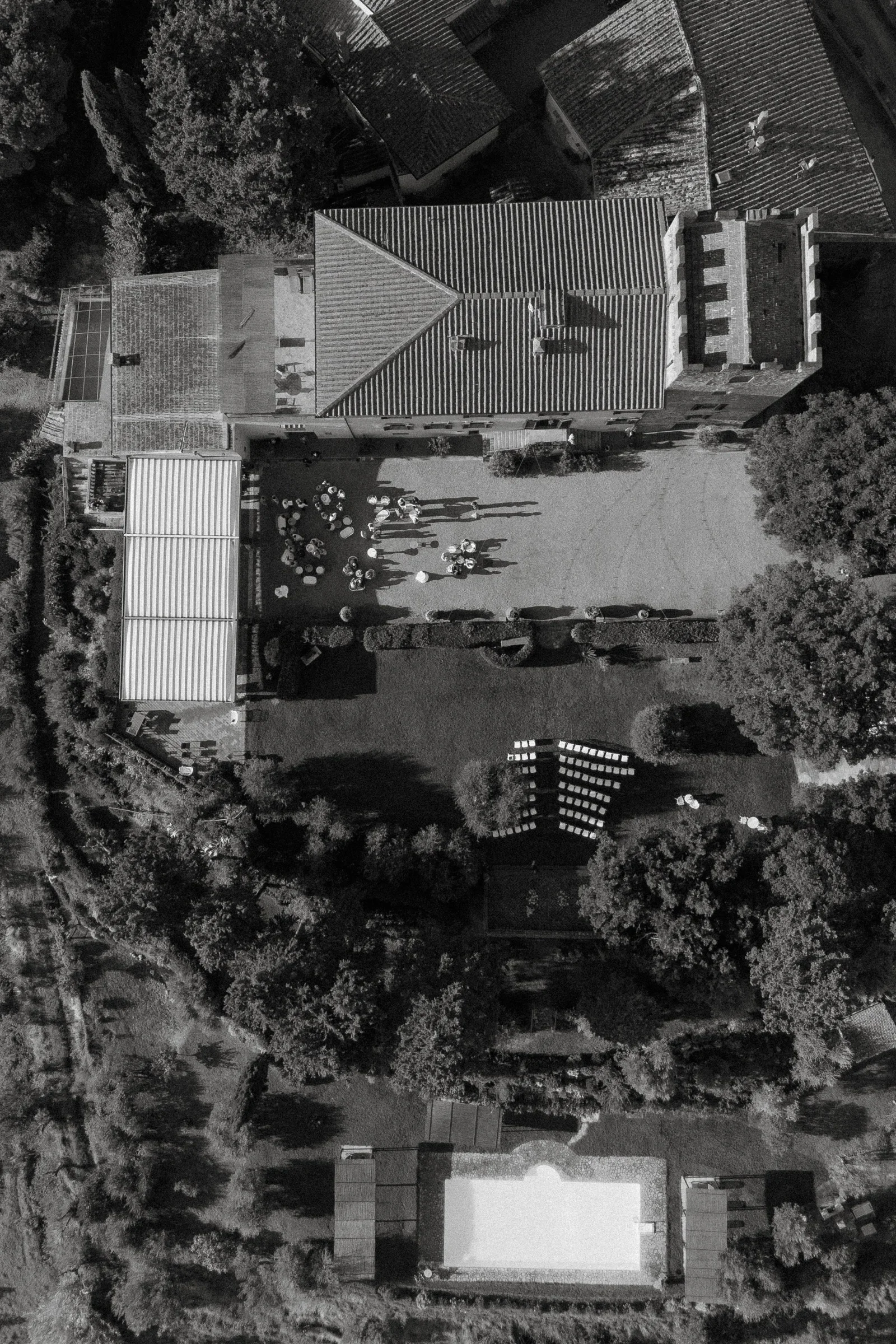 Overhead black and white frame of the villa's roofs, pool and gravel courtyard
