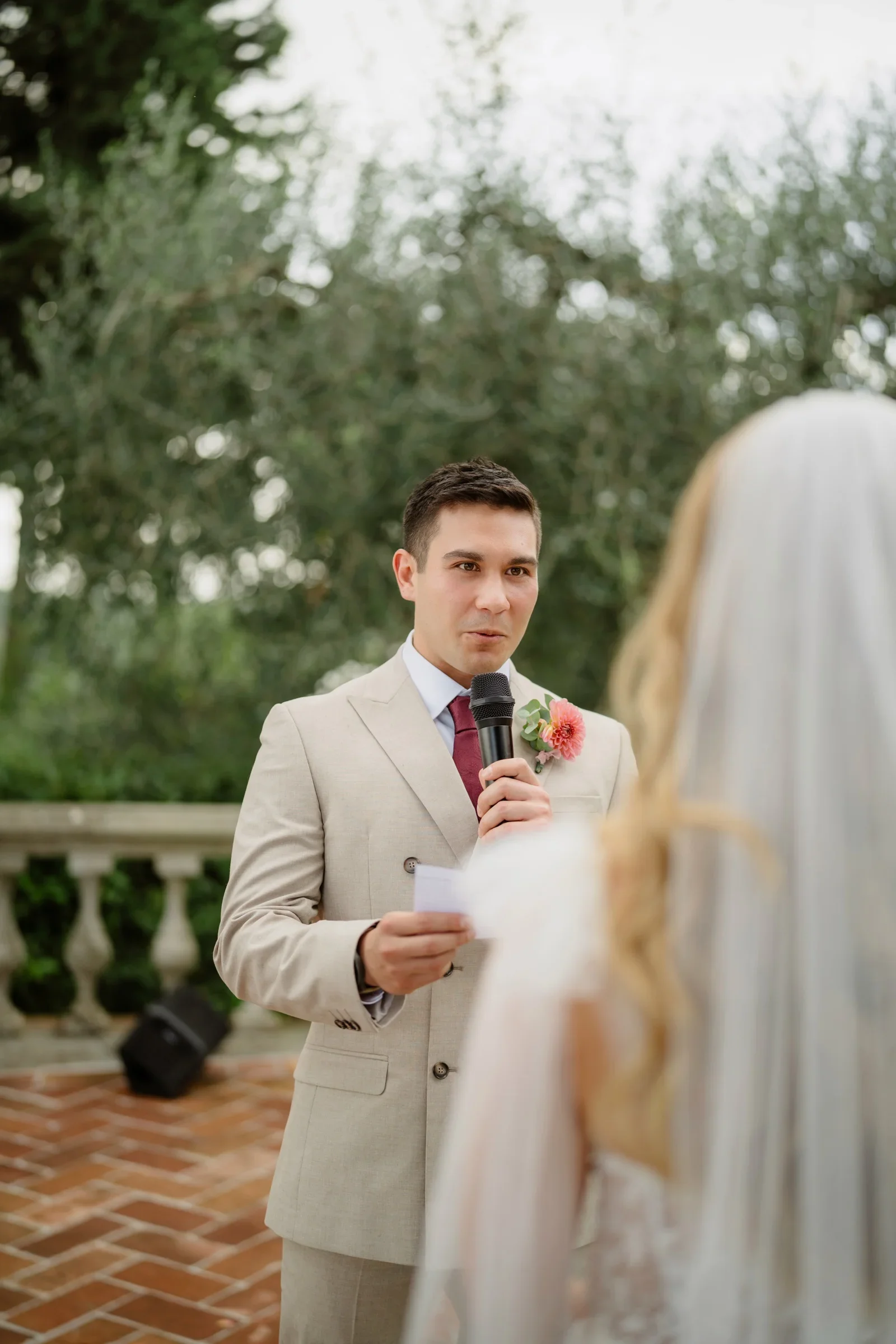 The groom reading his vows, the bride's veil in the foreground