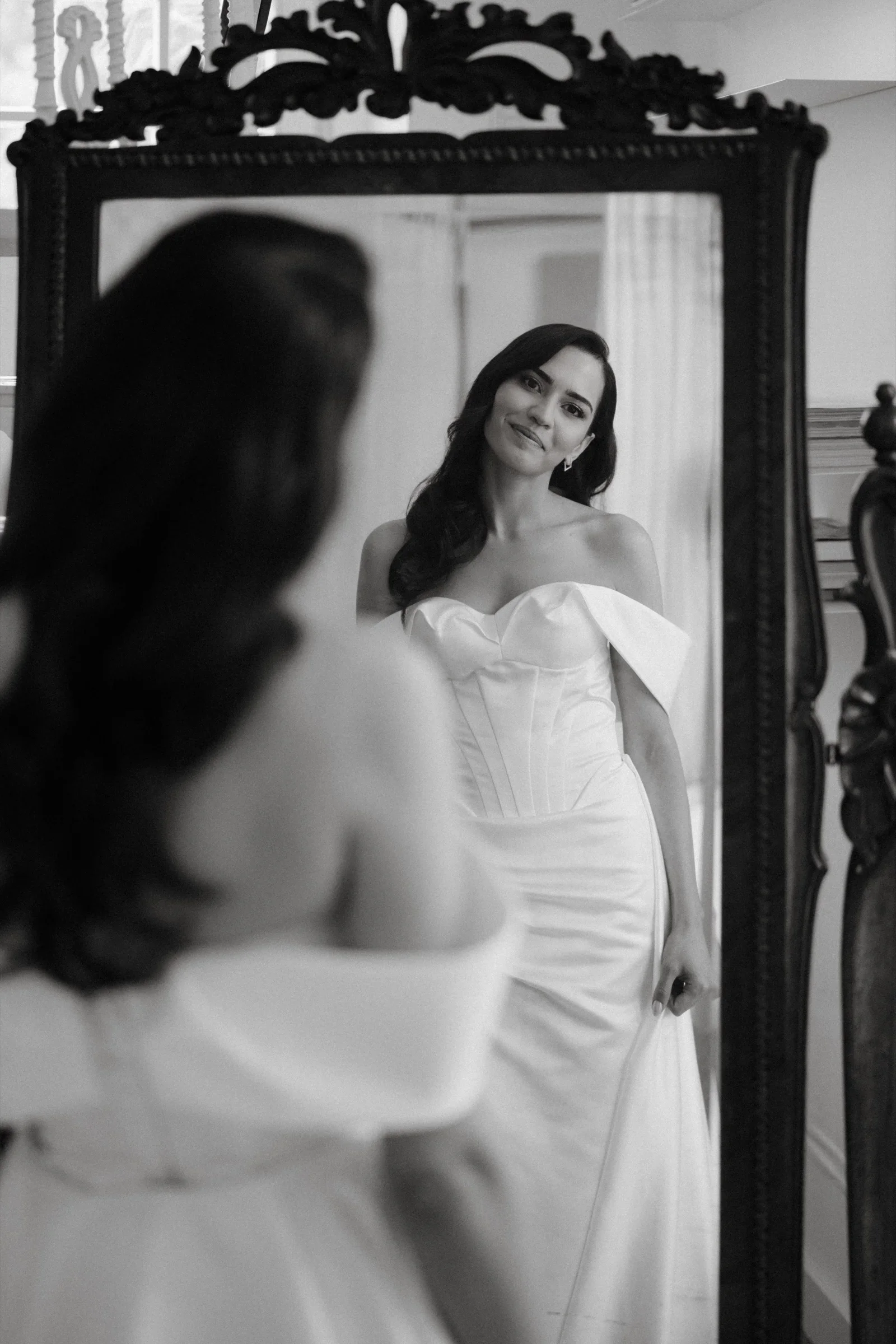 Black and white photo of the bride reflected in an ornate mirror