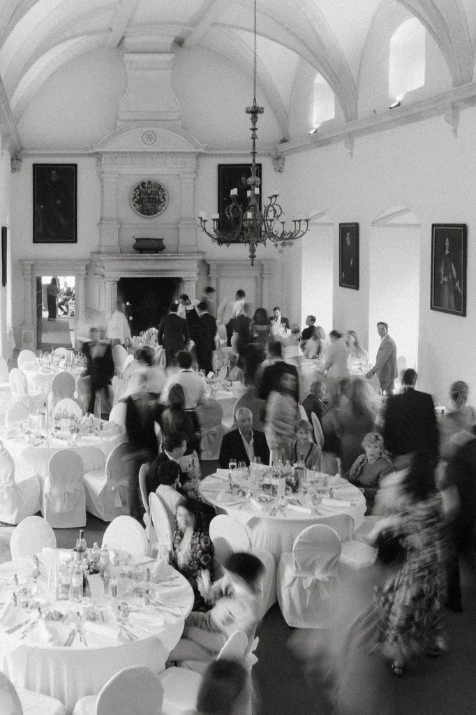Guests mingling in a vaulted reception hall beneath a chandelier