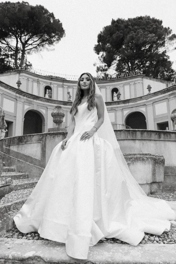 Bride on the steps of a domed villa, veil spread behind her