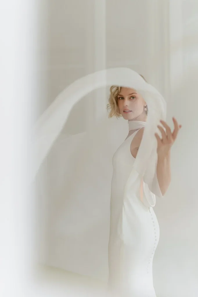 Bride catching her flowing veil in soft white light