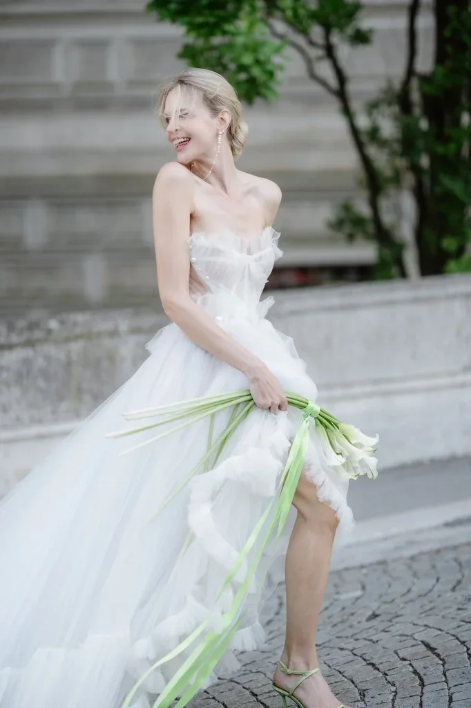 Bride laughing as she carries a loose bunch of calla lilies