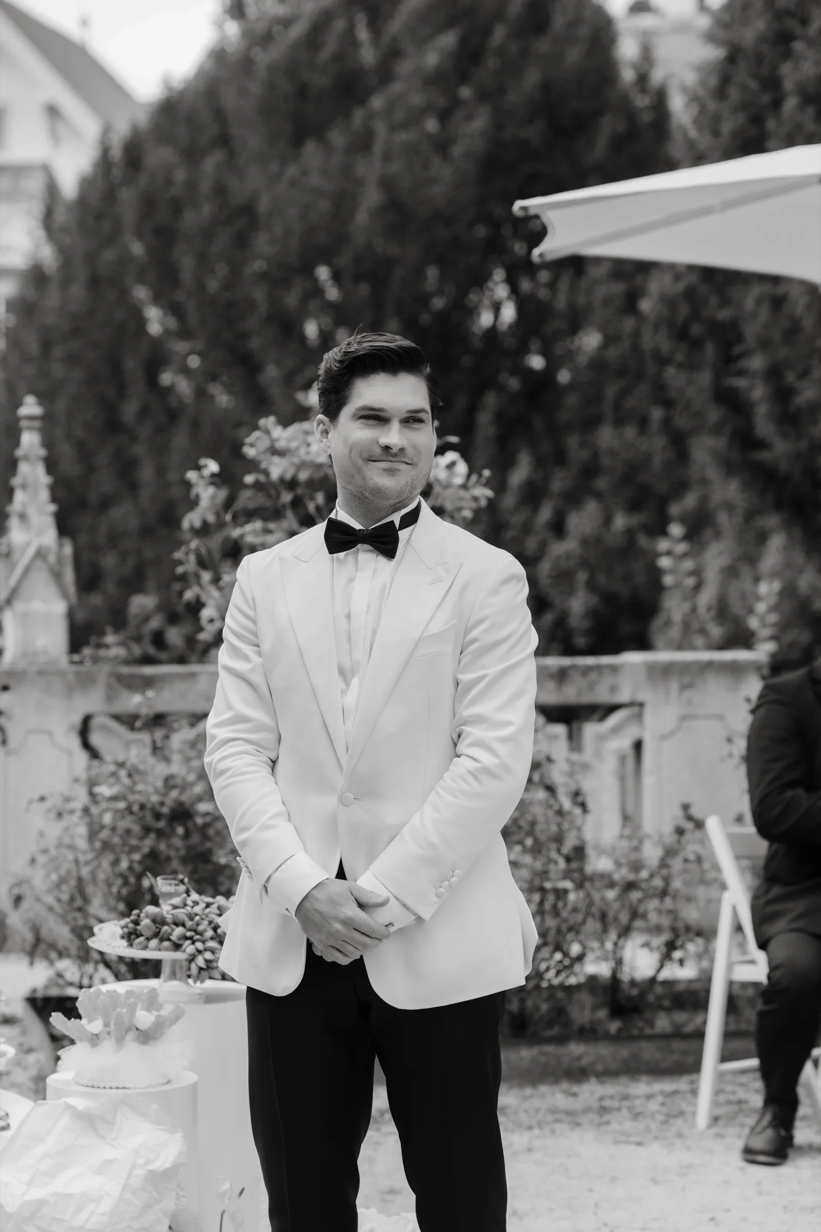 Black and white: the groom waiting at the end of the aisle, hands clasped