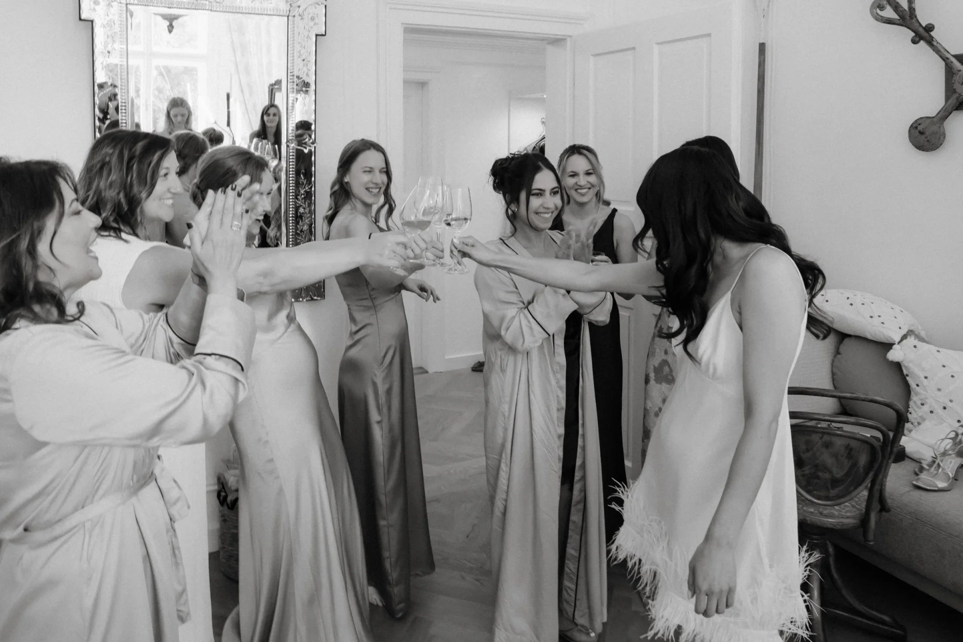 Black and white photo of bridesmaids and the bride cheering together with arms extended