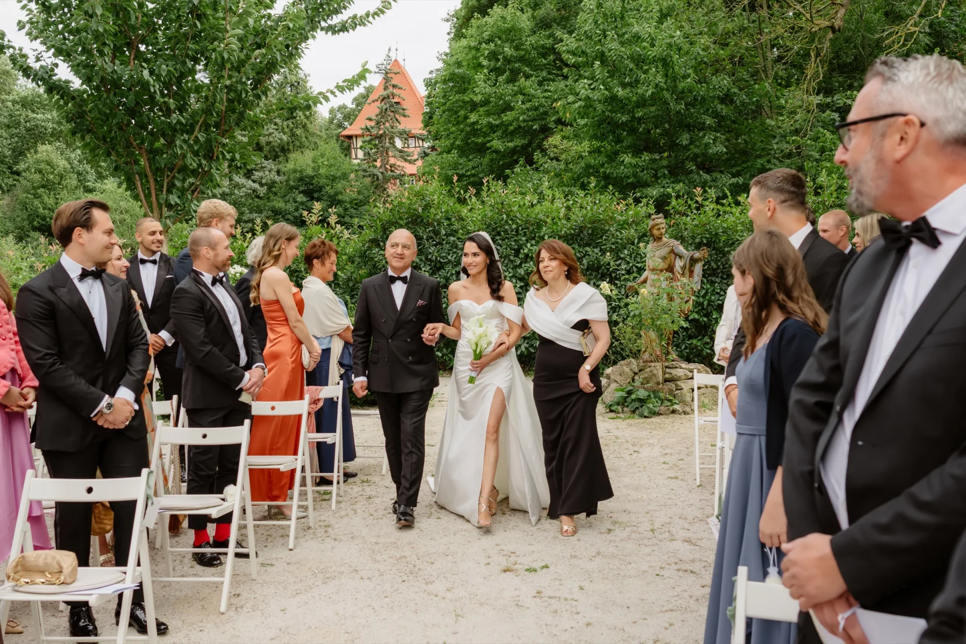 Bride walking down the aisle between rows of guests at the garden ceremony