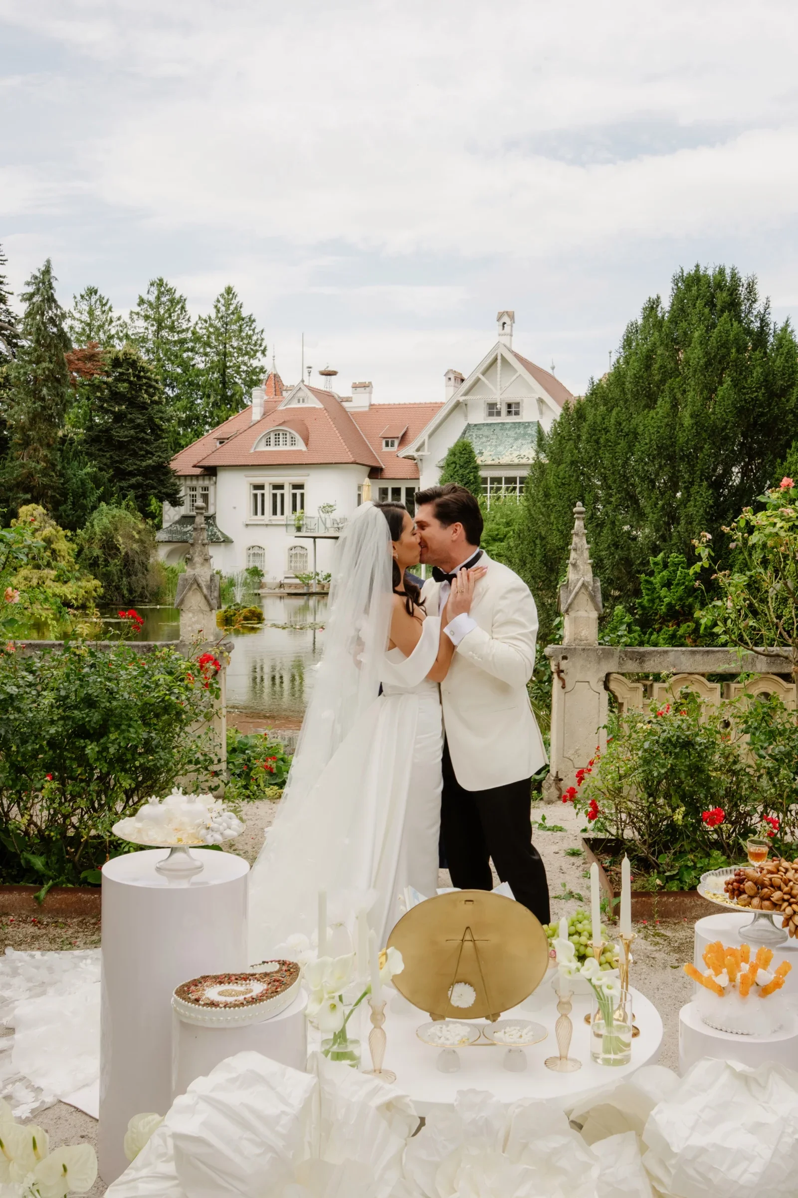 Couple standing at a ceremony table with flowers and a white villa behind