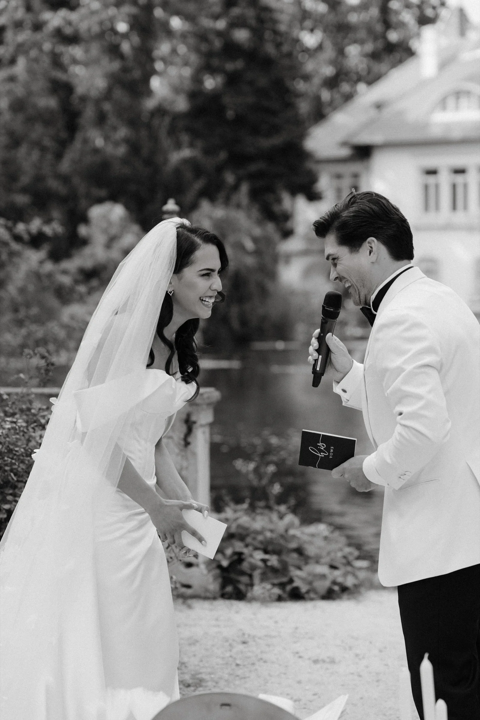 Black and white photo of the couple reading their vows in a garden