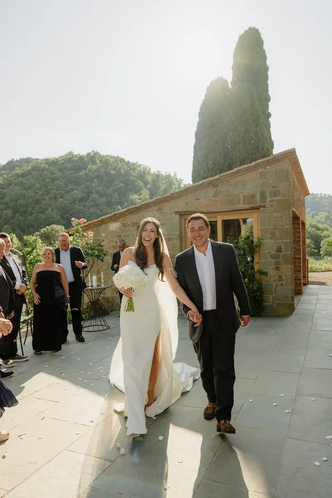 Newlyweds walking down a sunlit terrace after their ceremony