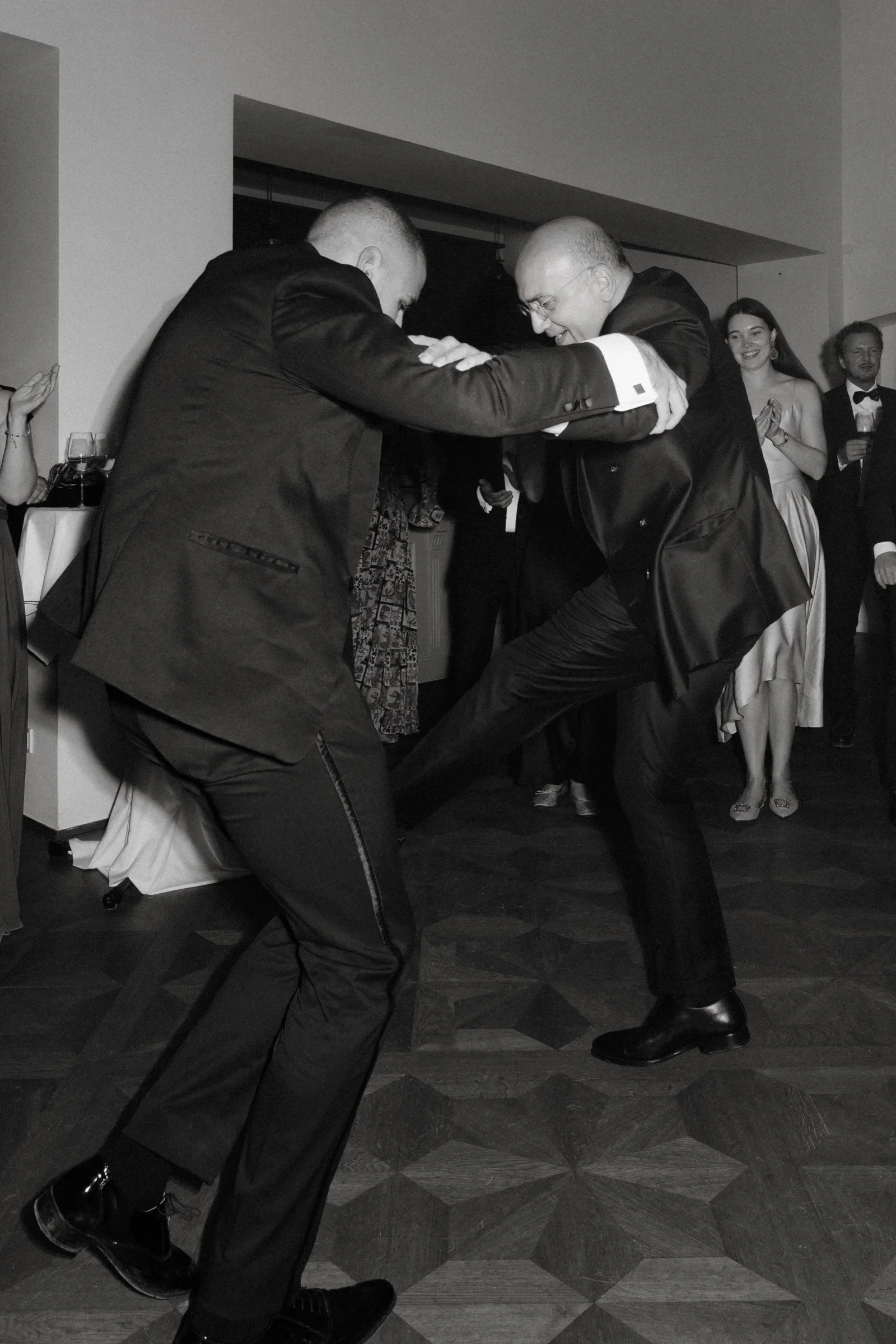 Two men in dark suits dancing close together, black and white