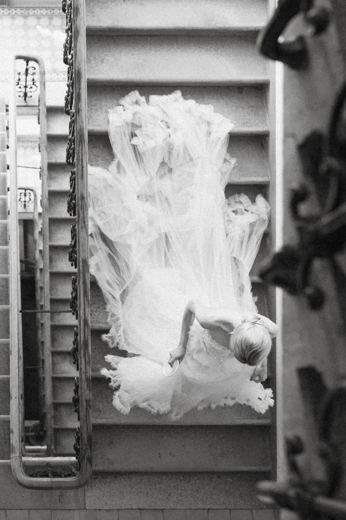 Bride in billowing tulle descending a stairwell, seen from above