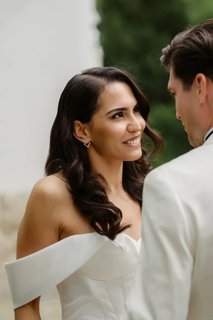 Bride smiling up at her groom in a white dinner jacket