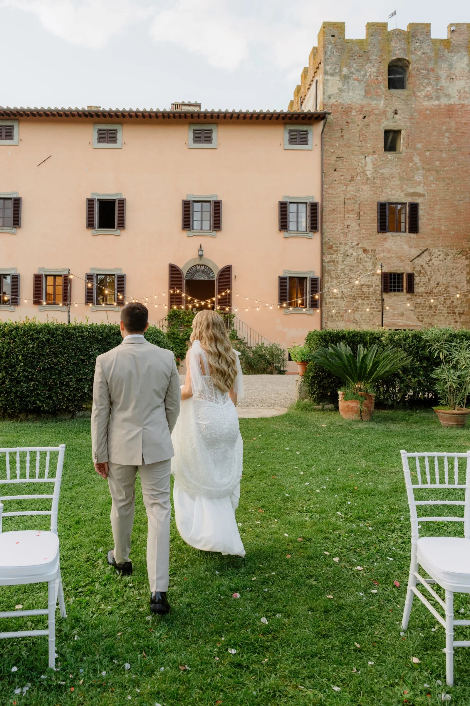 The couple walking back up the lawn towards the villa after the ceremony