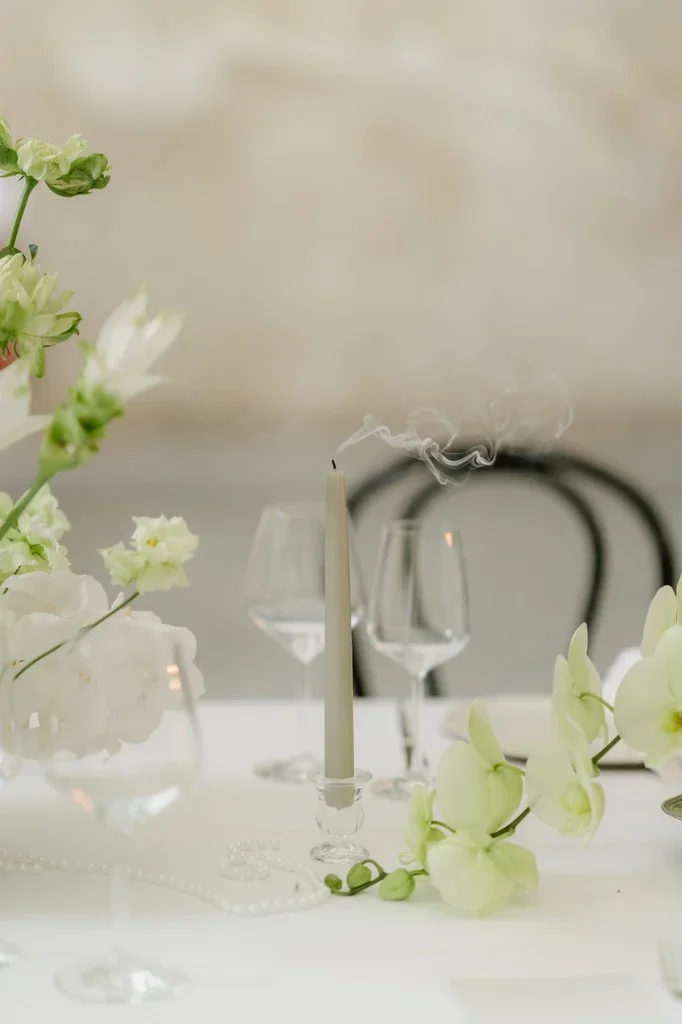 Just-blown-out candle and orchids on a softly set dining table