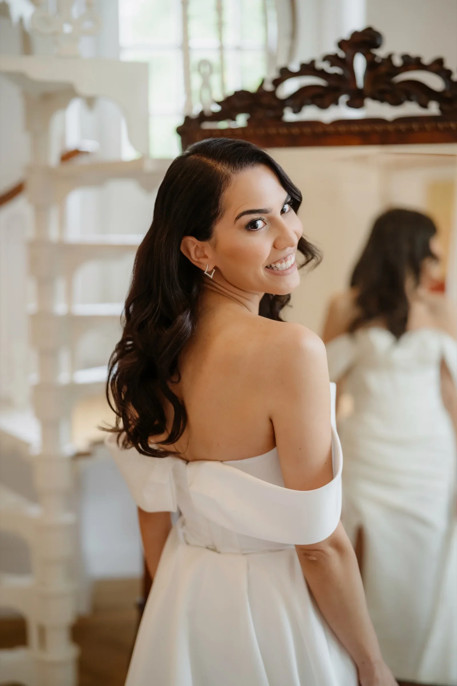 Smiling bride in an off-shoulder gown glancing over her shoulder