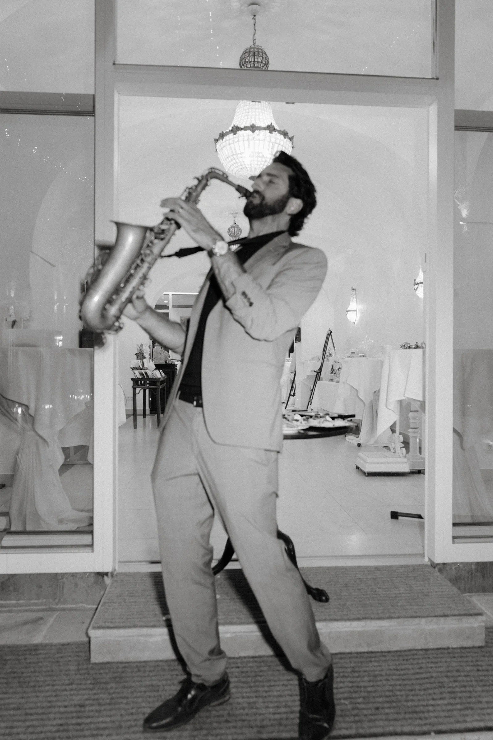 Guest playing a saxophone in a doorway, black and white