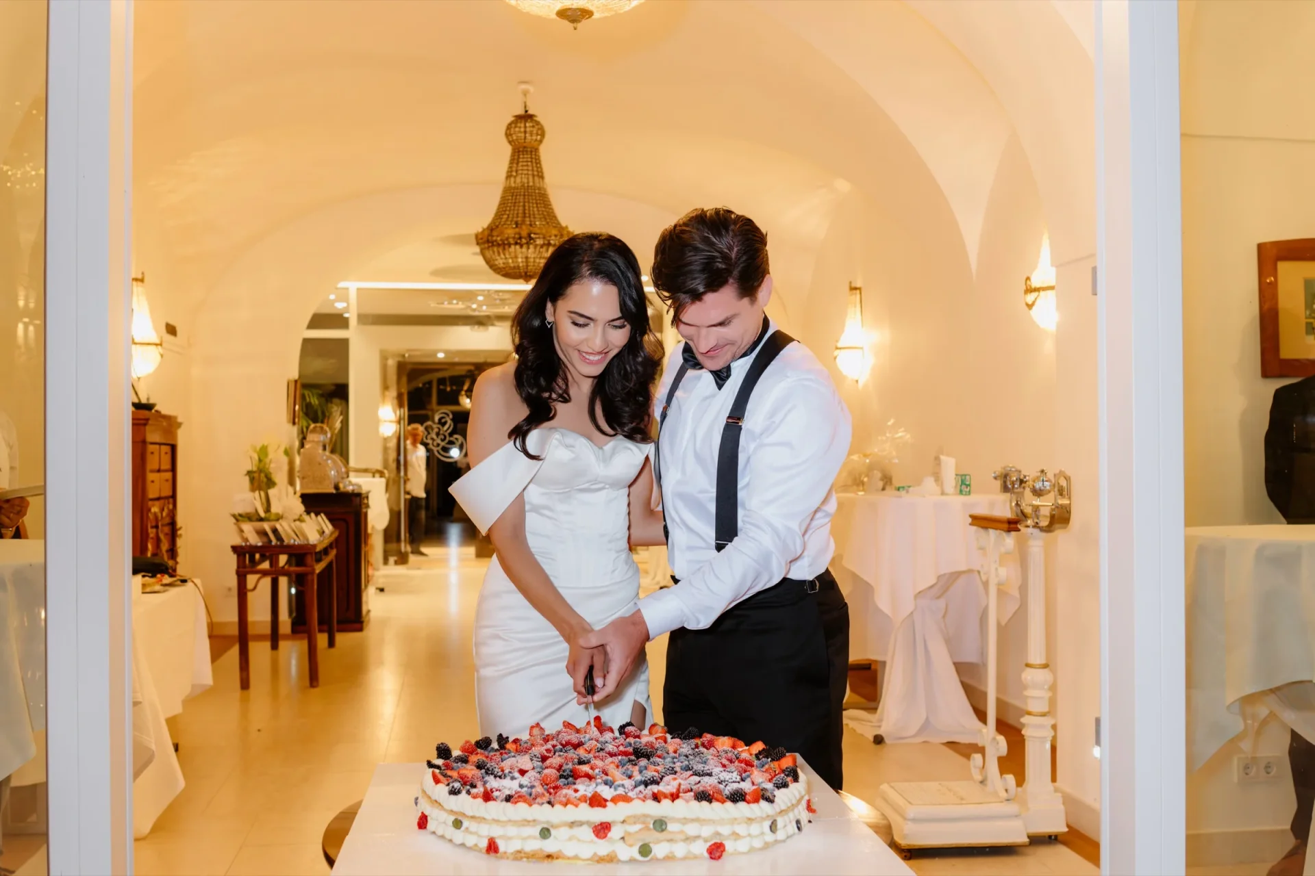 Bride and groom cutting a berry wedding cake in a vaulted room