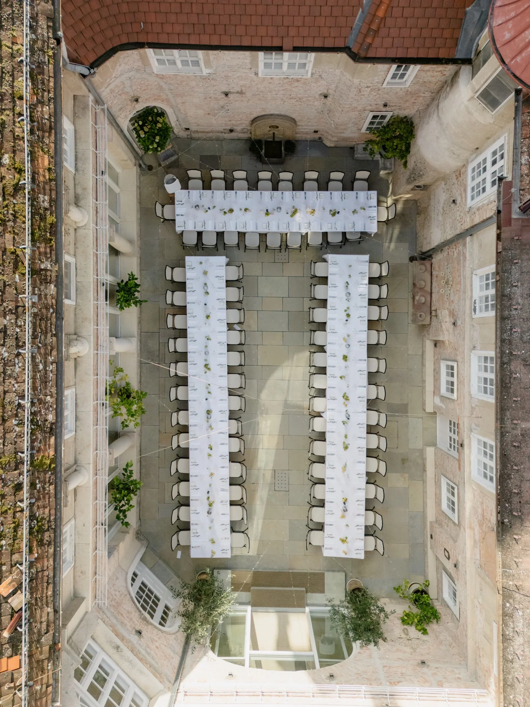 Aerial view straight down into the castle courtyard set with three long dinner tables