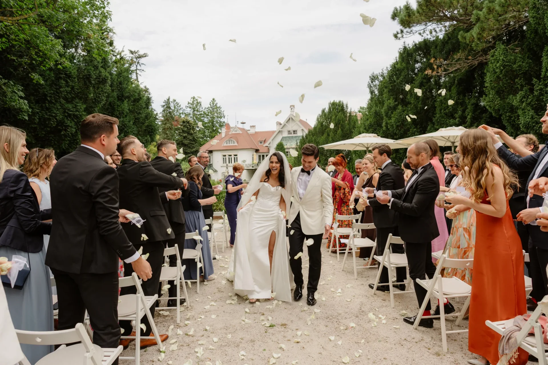 Couple walking up the aisle as guests throw petals and cheer