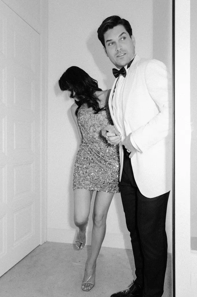 Playful couple in a hallway, she in a sequinned party dress