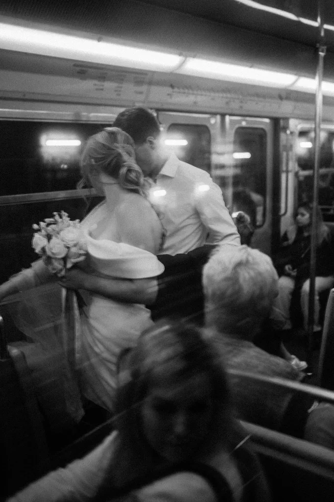 Bride and groom kissing on a crowded underground train
