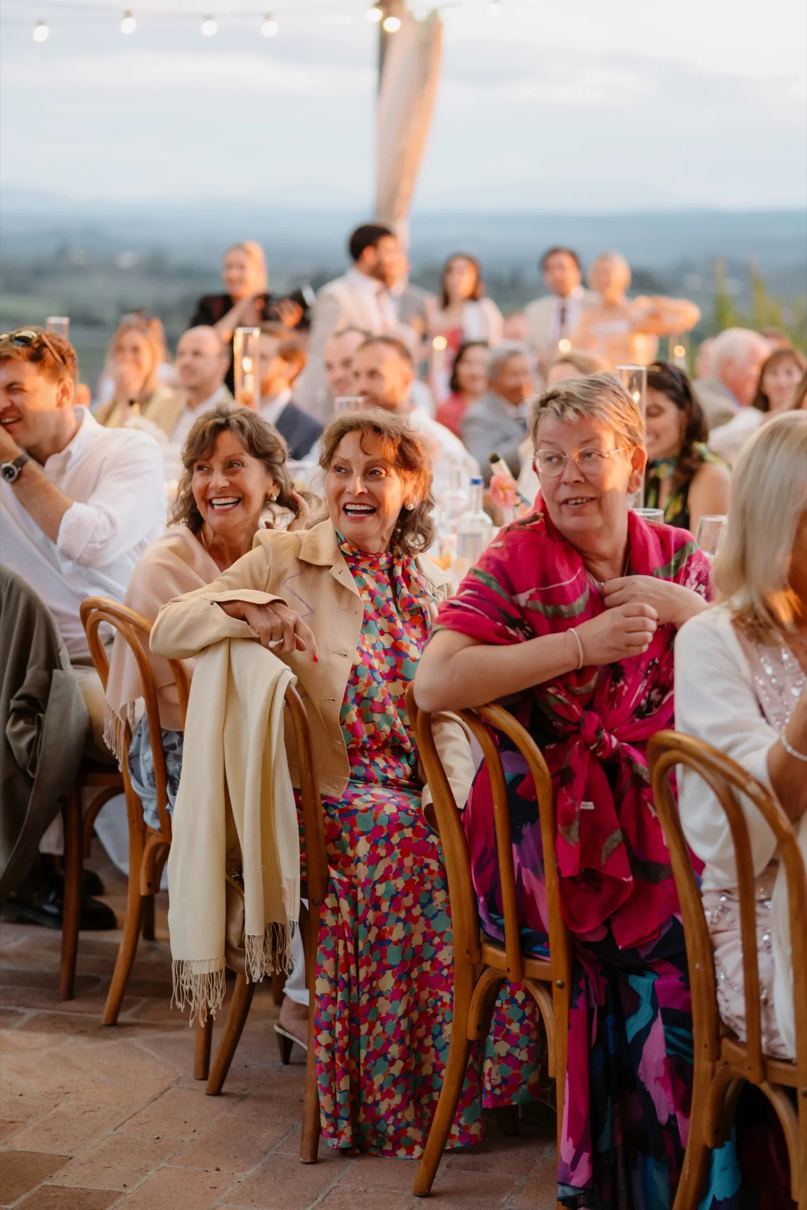 Guests listening to the speeches at the long table as the sun goes down
