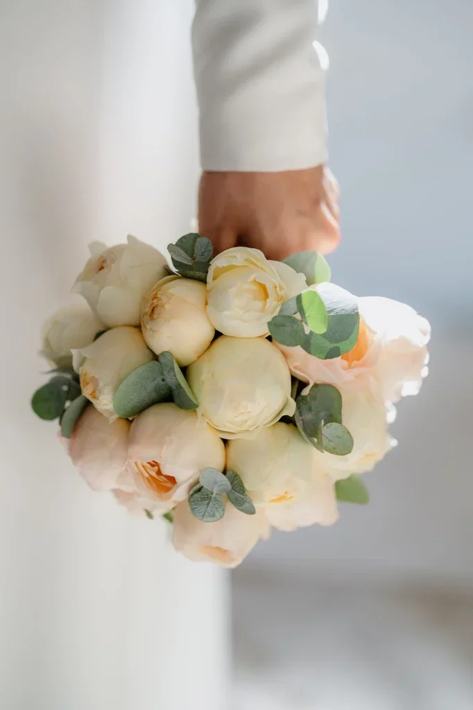 Bride holding a bouquet of cream peonies and eucalyptus