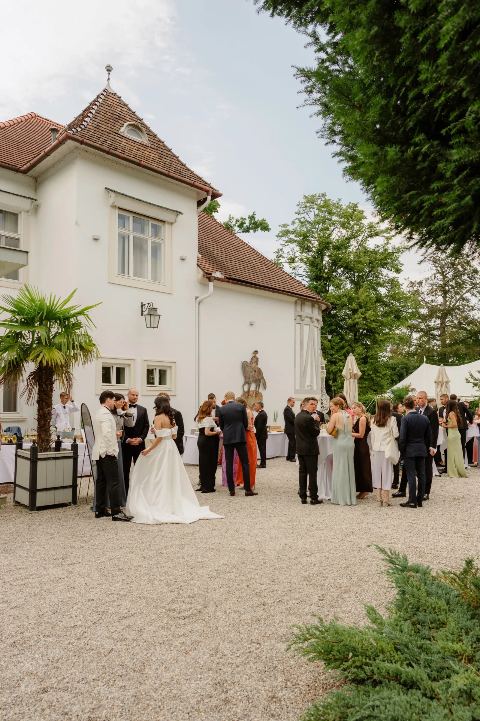 Bride and groom greeting guests in the gravel courtyard in front of the villa