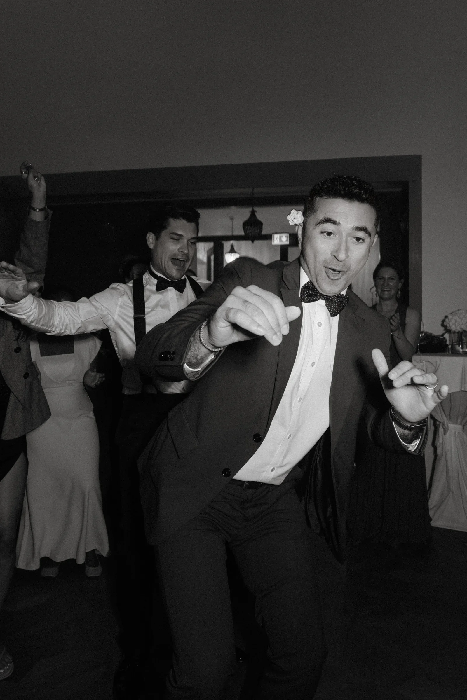 Guest in a suit dancing with a drink in hand, black and white